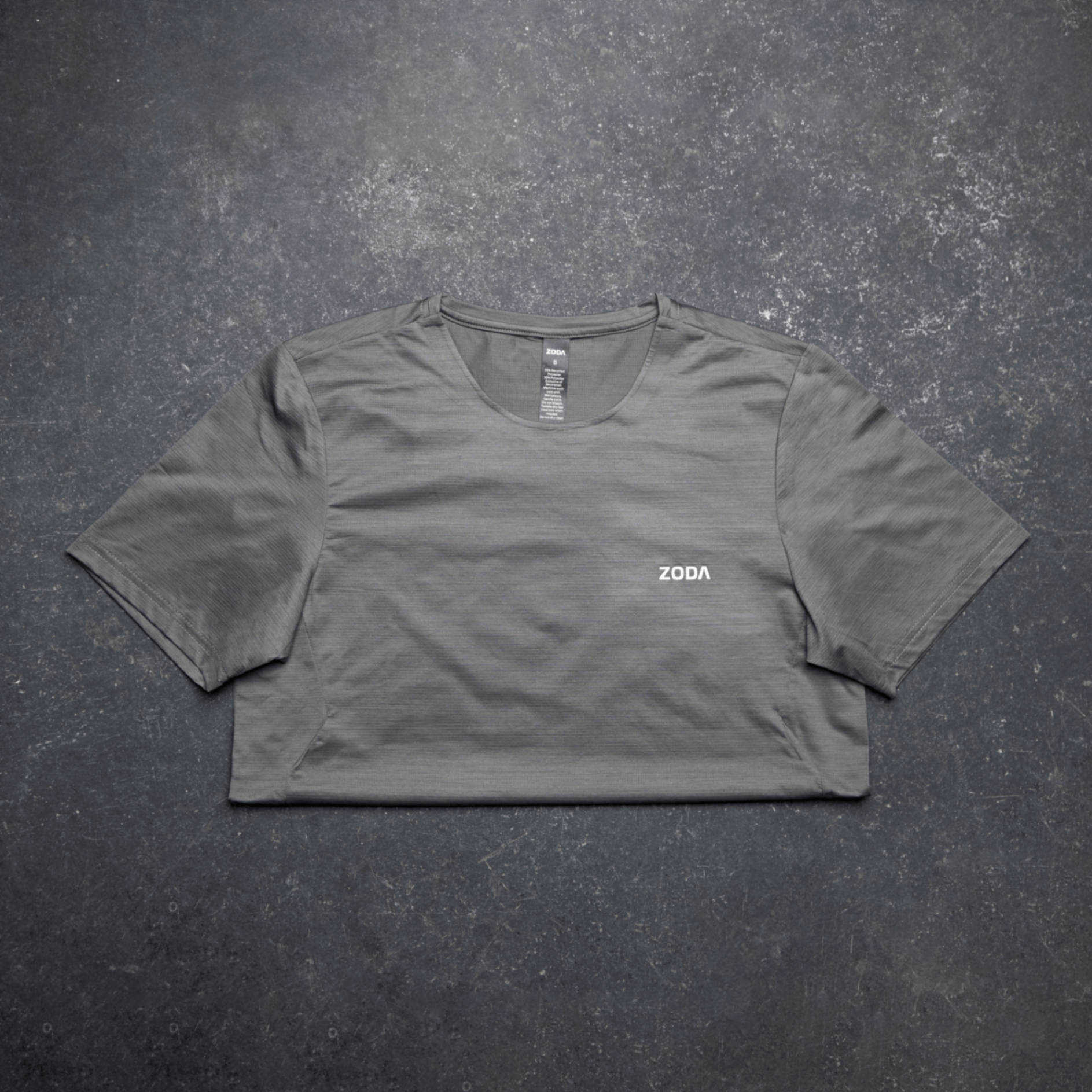 Gray t-shirt with 'ZODA' logo on a dark textured surface Zoda.sg