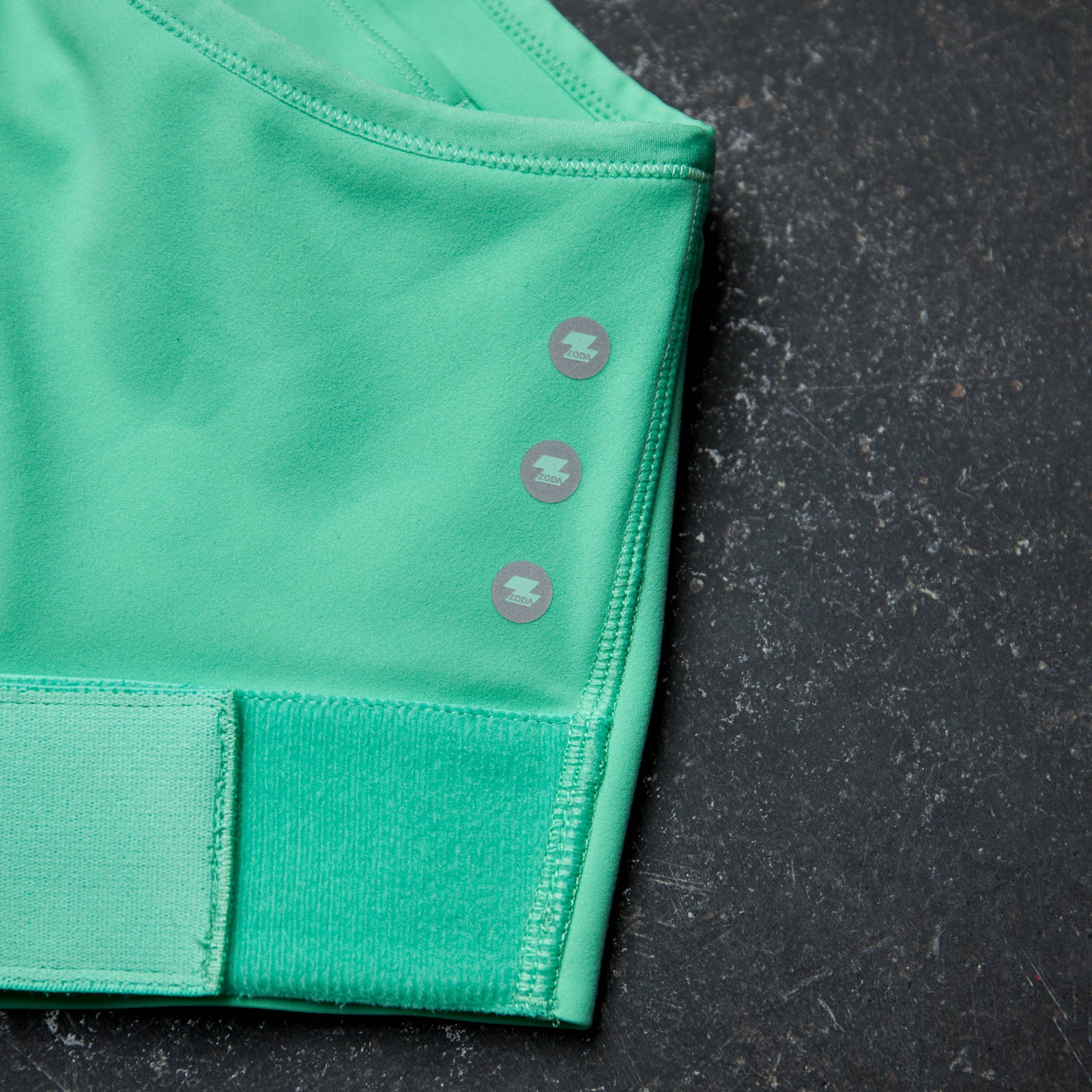 Green athletic top with button details on a black background