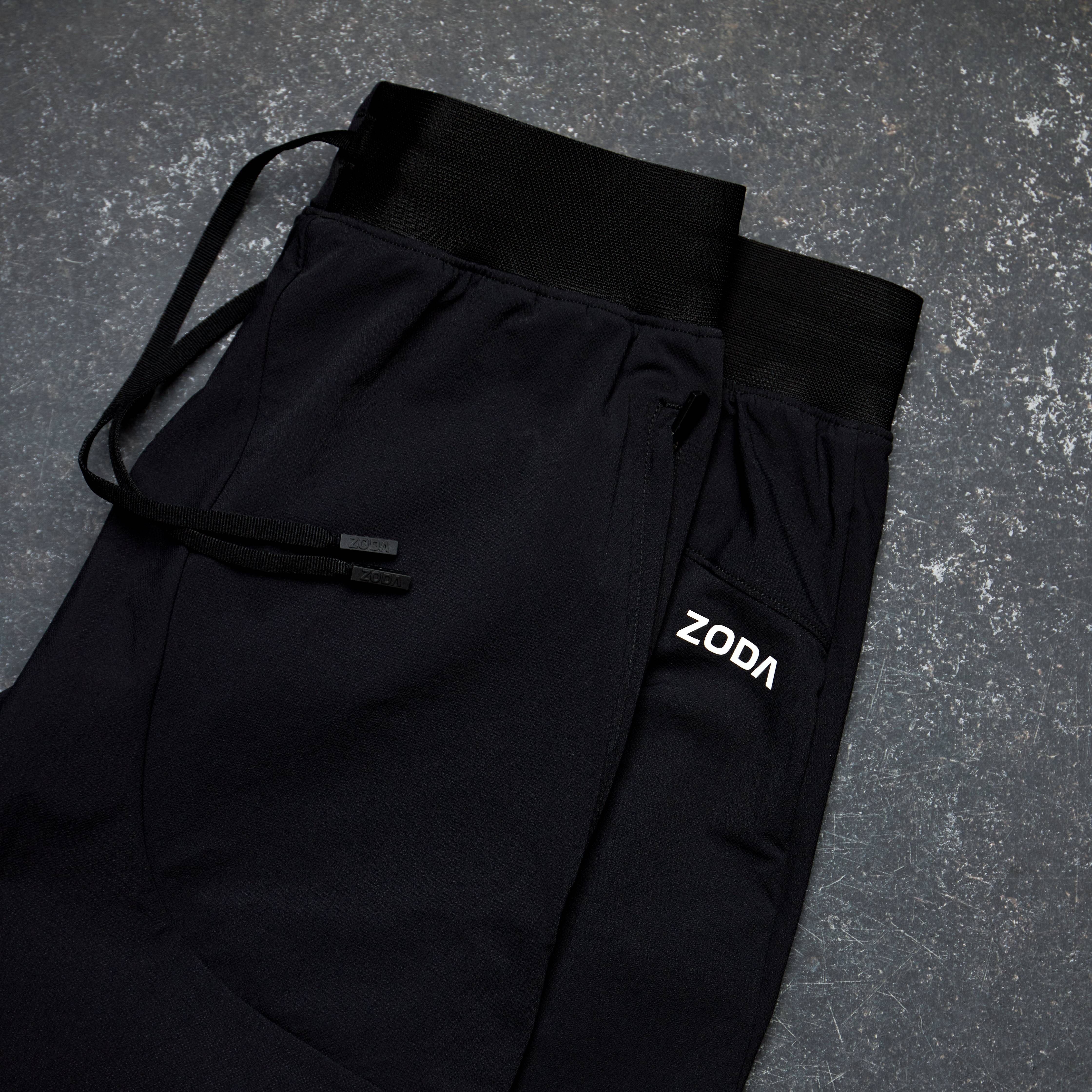 Black pants with a visible brand logo on a gray textured surface Zoda.sg