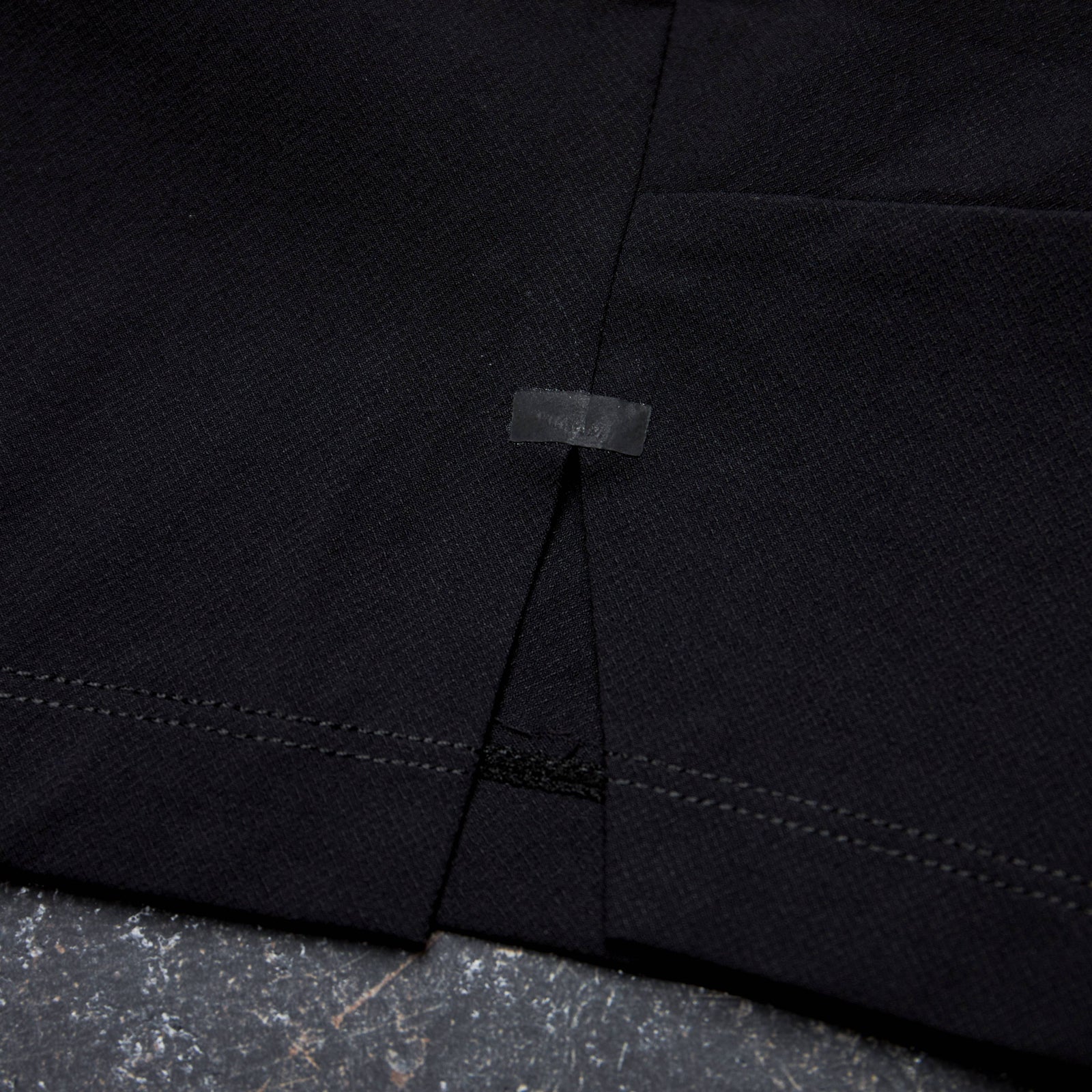 Close-up of a black fabric with stitching detail on a textured surface Zoda.sg