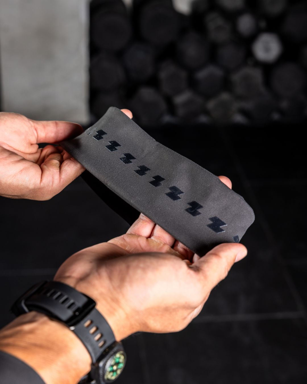 Person holding a black belt with a pattern against a dark background Zoda.sg