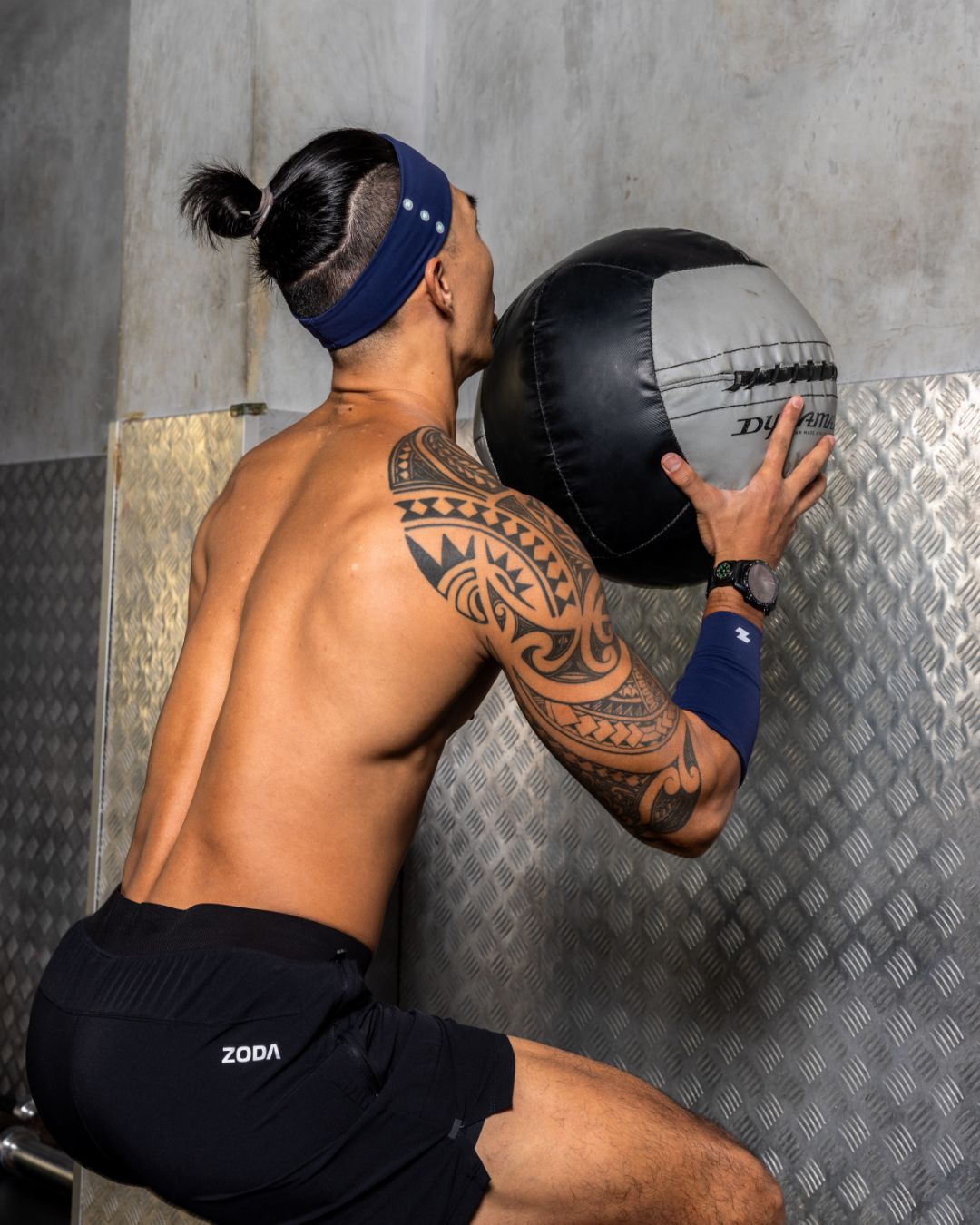 Man exercising with a medicine ball against a textured wall. Zoda.sg