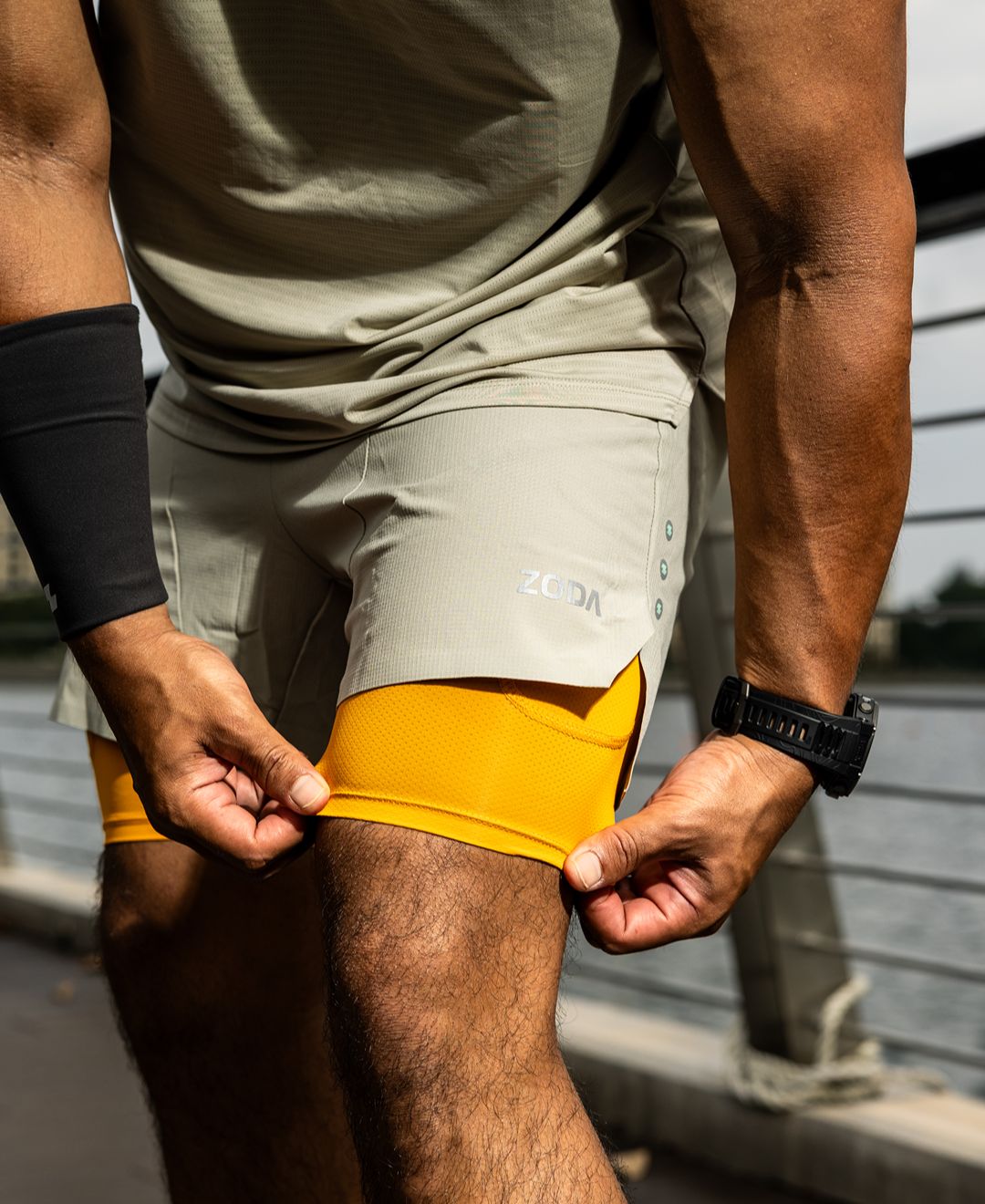 Person wearing gray shorts with yellow accents and a black wristband. Zoda.sg