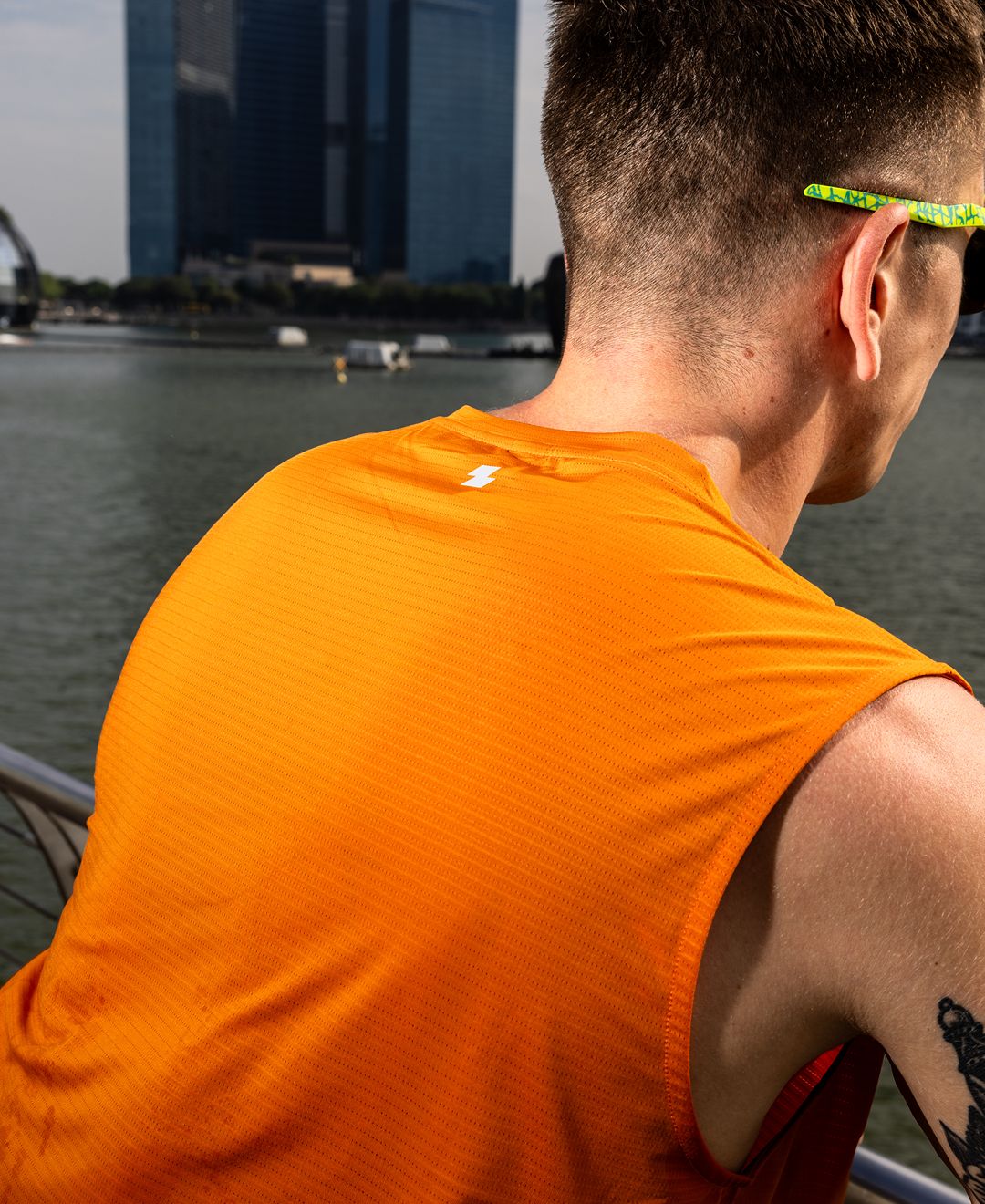 Person wearing an orange sleeveless shirt with a cityscape in the background Zoda Pulse Collection