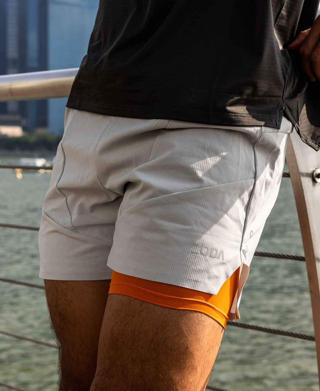 Person wearing gray shorts with orange underwear visible, standing on a boat. Zoda Pulse Collection