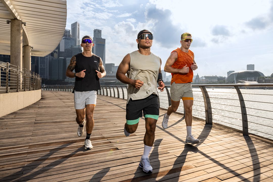 Three runners on a wooden pathway with a city skyline in the background Zoda.sg