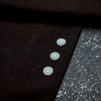 Close-up of a dark fabric with three buttons on a textured black surface Zoda.sg