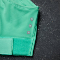 Green athletic top with button details on a black background