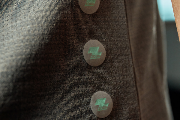 Close-up of a brown jacket with buttons featuring a logo. Performance wear - Zoda.sg In it to win it, Singapore