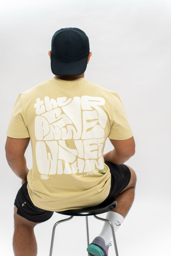 A person wearing a pale olive oversized tee with a graffiti print from the back. The text on the tee is not fully visible. Zoda.sg