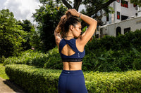 Woman in blue athletic wear stretching outdoors with greenery and buildings in the background Zoda.sg
