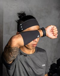 Person wearing black sweatbands on head and arms, with a gray background Zoda.sg
